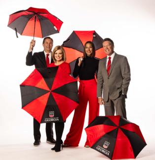 UGA ATSC Alumni pose with red and black umbrellas for a group photo