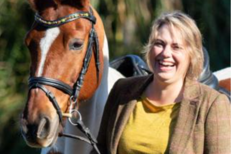 Dr. Trauger laughs, standing next to a horse