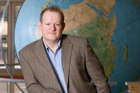 Dr. Herod poses in front of the Geography globe