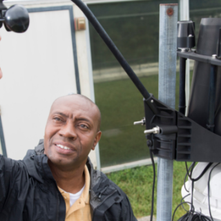 Professor Marshall Shepherd checks a weather station on top of the roof of the Geography Building.