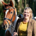 Dr. Trauger laughs, standing next to a horse