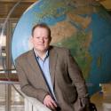 Dr. Herod poses in front of the Geography globe